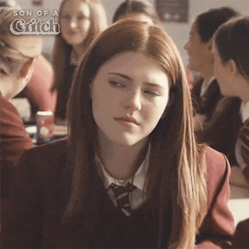 a girl in a school uniform is sitting in a classroom with her eyes closed