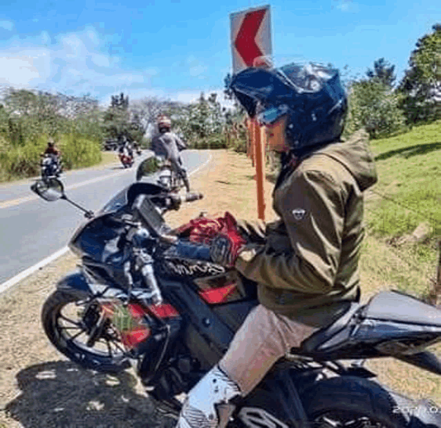 a man wearing a helmet is sitting on a motorcycle on the side of a road .