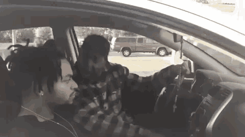 two men are sitting in a car and talking .