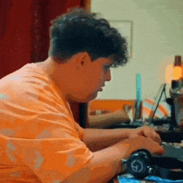 a man with curly hair is sitting at a desk with headphones on .