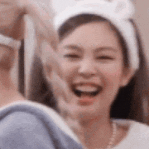 a close up of a woman wearing a white headband making a heart shape with her hands .