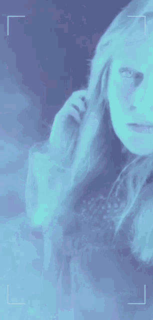 a girl with long blonde hair is taking a picture with a blue background