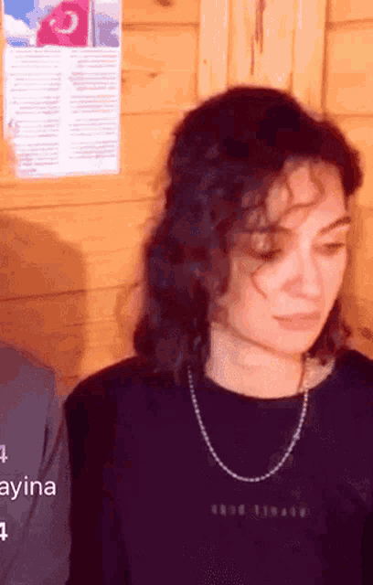 a woman with curly hair wearing a black shirt with the word ayina on it