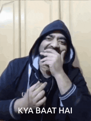 a man wearing a hooded jacket is laughing with the words kya baat hai behind him