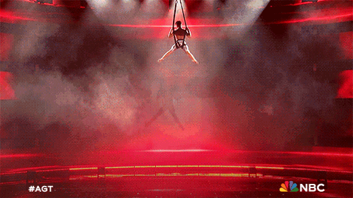 a person is hanging from a rope on a stage with the nbc logo on the bottom