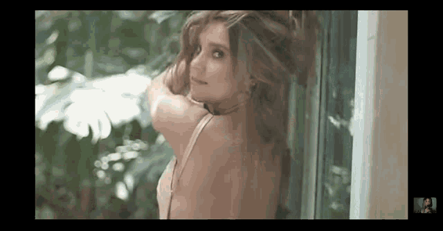a woman in lingerie is standing in front of a window and looking at the camera