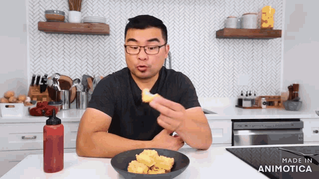a man is eating food in a kitchen with a bottle of ketchup on the counter