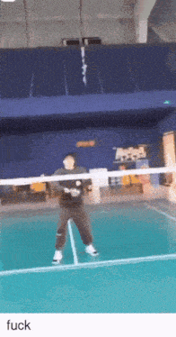 a man is playing badminton on a court with the word fuck underneath him