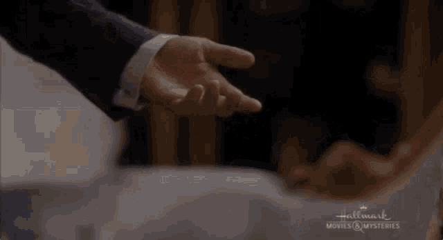 a man in a suit holds a woman 's hand in a hallmark movie