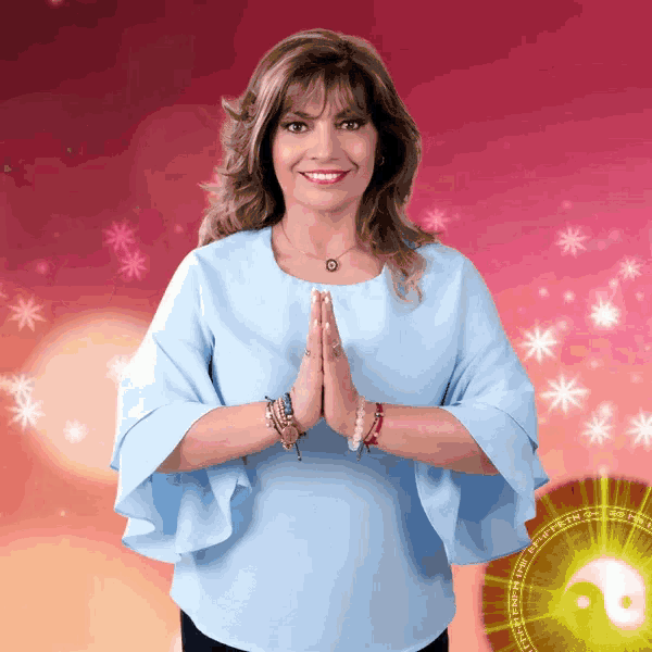 a woman in a blue shirt is standing with her hands folded in front of a yin yang symbol