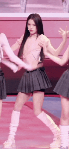 a woman in a pleated skirt is dancing on a stage with other girls .