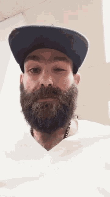 a man with a beard wearing a hat and a necklace