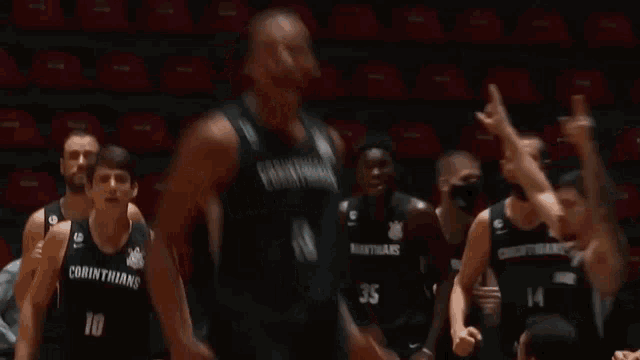 a basketball player in a corinthians jersey stands on the court