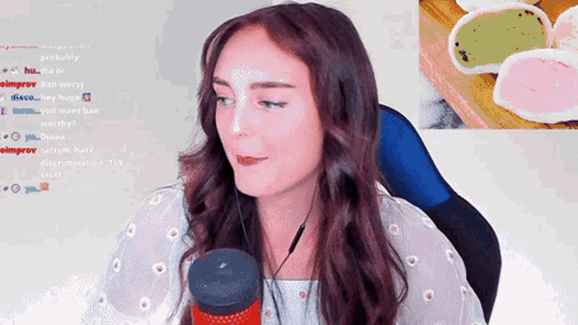 a woman sitting in front of a microphone with a picture of a plate of mochi in the background