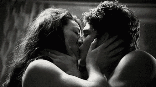 a black and white photo of a man and woman kissing each other .