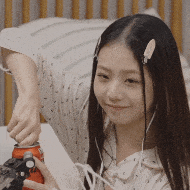 a girl wearing ear buds is opening a can of coca cola