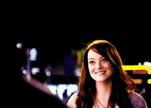 a woman is smiling and giving a thumbs up at night