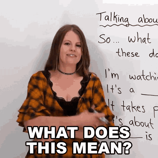 a woman is standing in front of a white board with the words what does this mean written on it