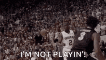 a basketball game is being played in front of a crowd of people and a referee .