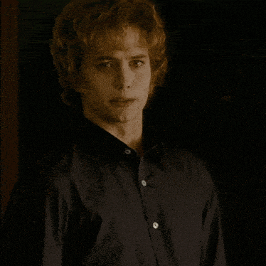 a man with red hair is wearing a black shirt with white buttons