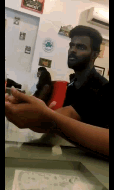 a man sitting at a table with a sign that says whiskey on the wall