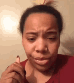 a woman with a nose ring is making a funny face while holding a lipstick .