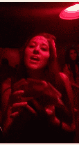 a woman in a dark room with a red light above her head