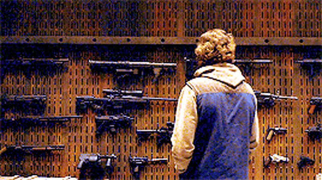 a man is looking at a wall full of guns .
