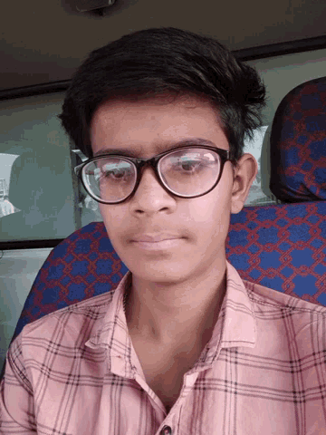 a young boy wearing glasses and a plaid shirt looks down at the camera