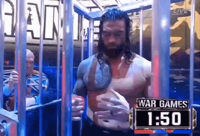 a wrestler is standing in a cage with a sign that says war games 1:50 .