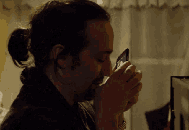 a man with long hair and a beard looks at a cell phone