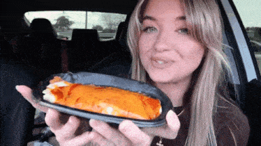 a woman in a car is holding a tortilla in her hand