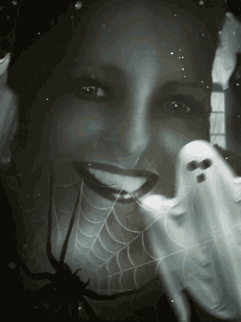 a woman is smiling while holding a ghost and a spider web