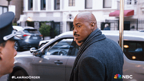 a man in a grey coat is talking to a police officer in a law and order ad