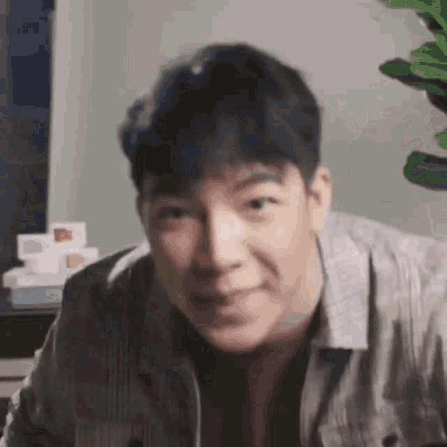 a man in a plaid shirt is making a funny face while looking at the camera .