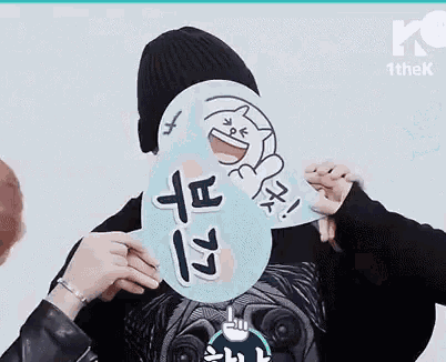 a person is holding a sign in front of their face that says `` i love you '' .
