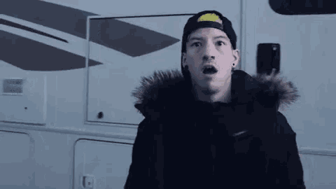 a man wearing a black jacket and a hat is standing in front of a rv .
