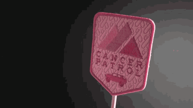 a pink patch that says cancer patrol is on a stick