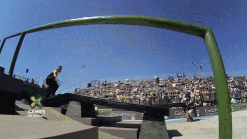 a skateboarder is doing a trick in front of a crowd at a gopro sponsored event