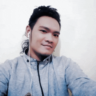 a man wearing ear buds and a gray jacket takes a selfie