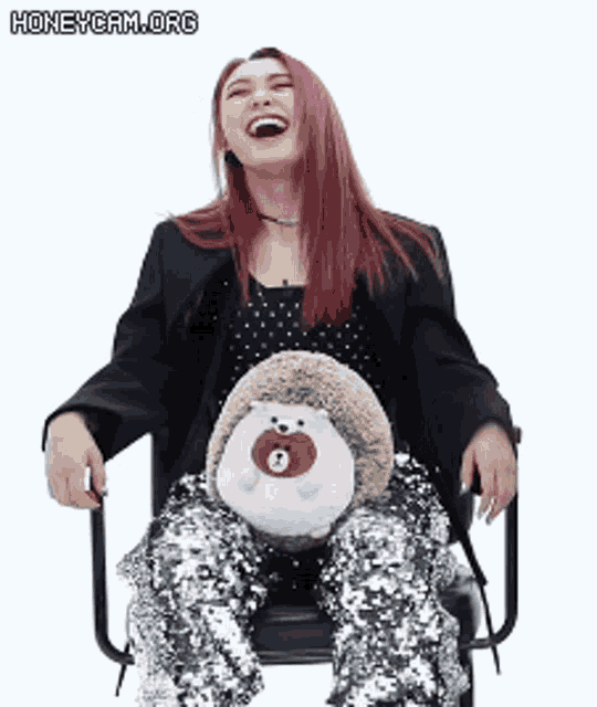 a woman is sitting in a chair holding a stuffed hedgehog