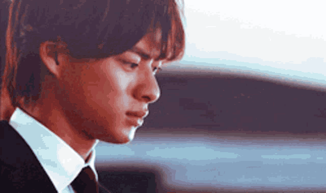 a young man in a suit and tie is looking down .