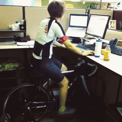 a man is sitting on a bike in front of a desk