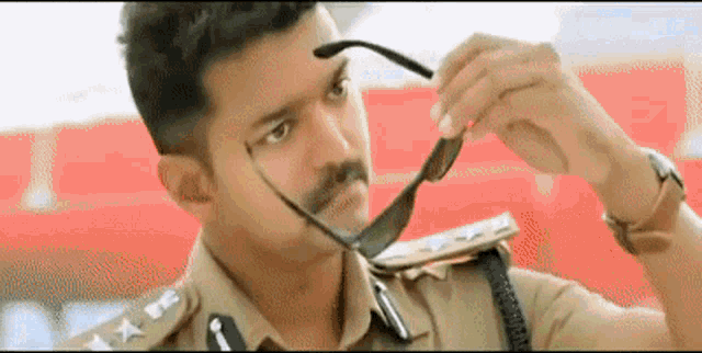 a man in a police uniform is adjusting his glasses