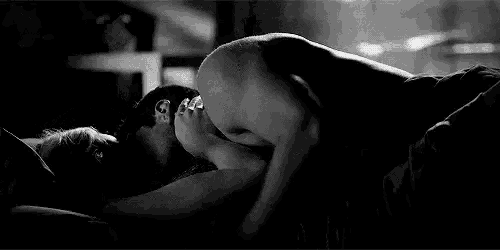 a black and white photo of a man and a woman having sex in bed .