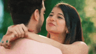 a man and a woman are looking at each other and hugging .