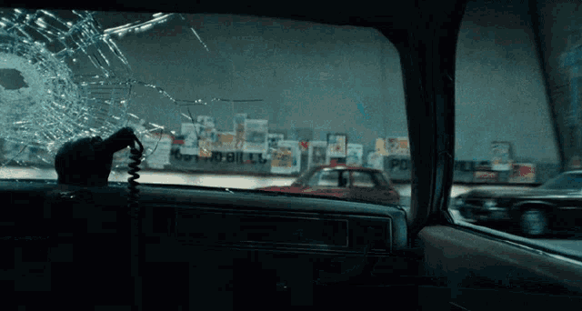 a car with a broken windshield and a phone hanging out of it