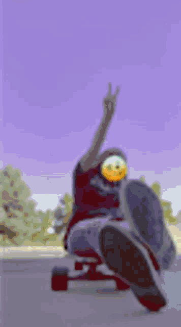 a person is sitting on a skateboard and giving a peace sign