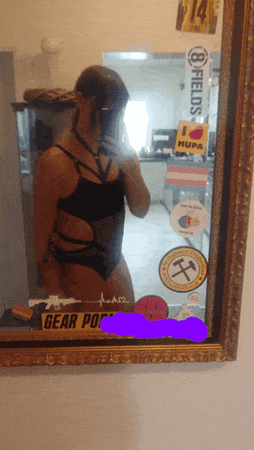 a woman is taking a selfie in front of a mirror that has stickers on it including one that says gear police
