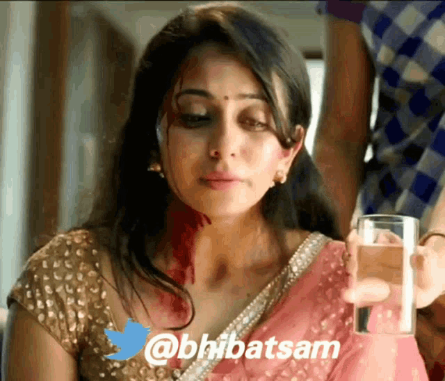 a woman in a pink saree is holding a glass of water with the twitter username @bhibatsam